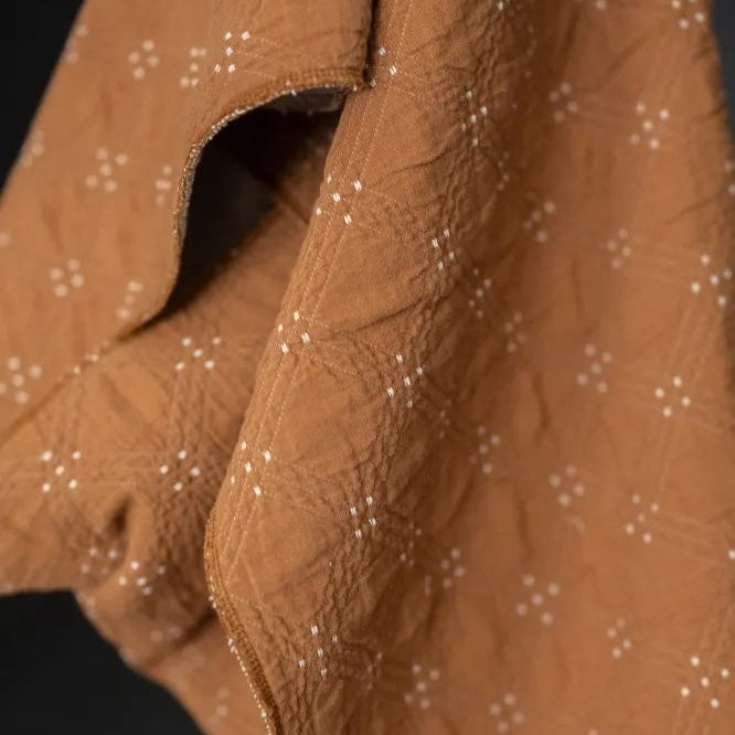 Goldie quilted cotton jacquard fabric in ochre and cream, reversible double-cloth texture, with cream embroidered details.