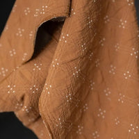 Goldie quilted cotton jacquard fabric in ochre and cream, reversible double-cloth texture, with cream embroidered details.