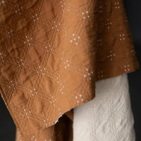 Goldie quilted cotton jacquard fabric in ochre and cream, reversible double-cloth texture, with cream embroidered details.