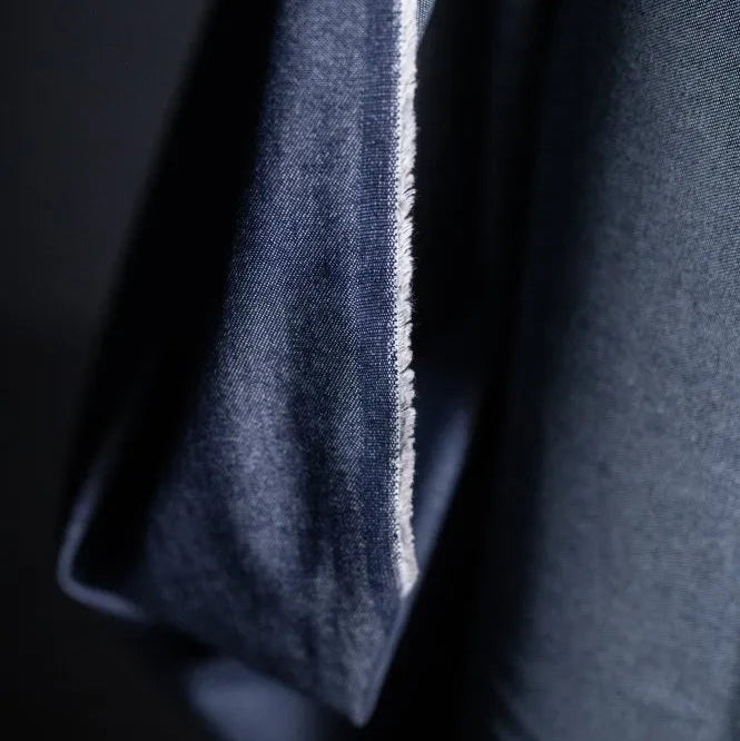Merchant and Mills 8oz Washed Denim in Dark. The fabric is draped over the roll and the image is a close up of the selvedge.