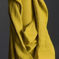 European Laundered Linen 185gsm in Mr Citrus by Merchant & Mills. The image is of the fabric draped over the fabric roll with a dark background.  Stitch Piece Loop Australian Fabric Store.