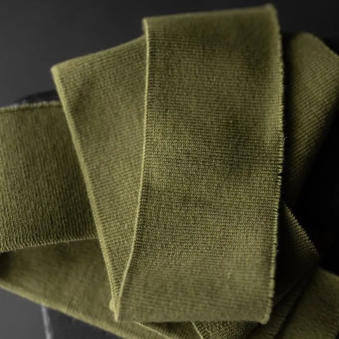 Orchard Green Cotton Ribbing by Merchant and Mills. Available at Stitch Piece Loop, Australia. The image is a close up of the pine green coloured ribbing against a dark background.