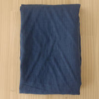 A folded piece of dark blue linen fabric laid flat on a light-colored wooden surface.