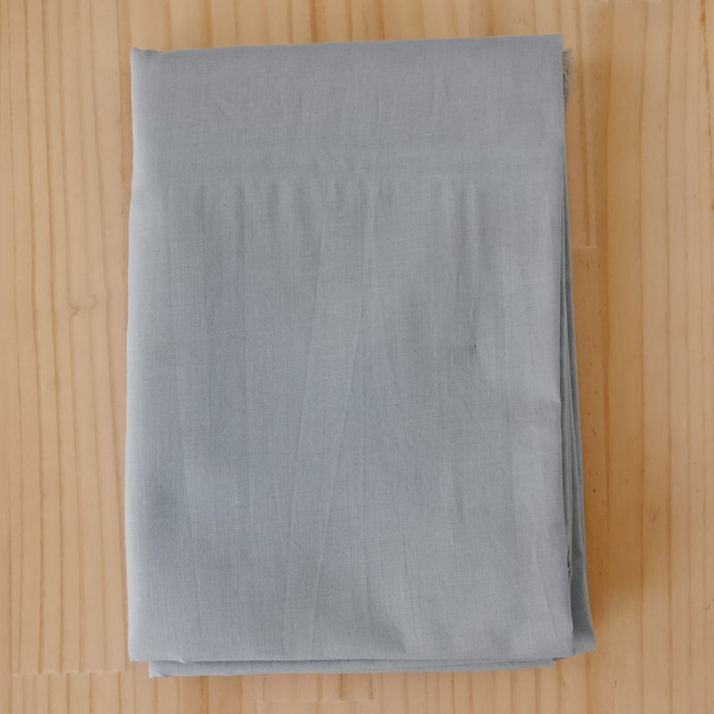 Folded light gray cotton voile fabric, displayed flat on a light-colored wooden surface.