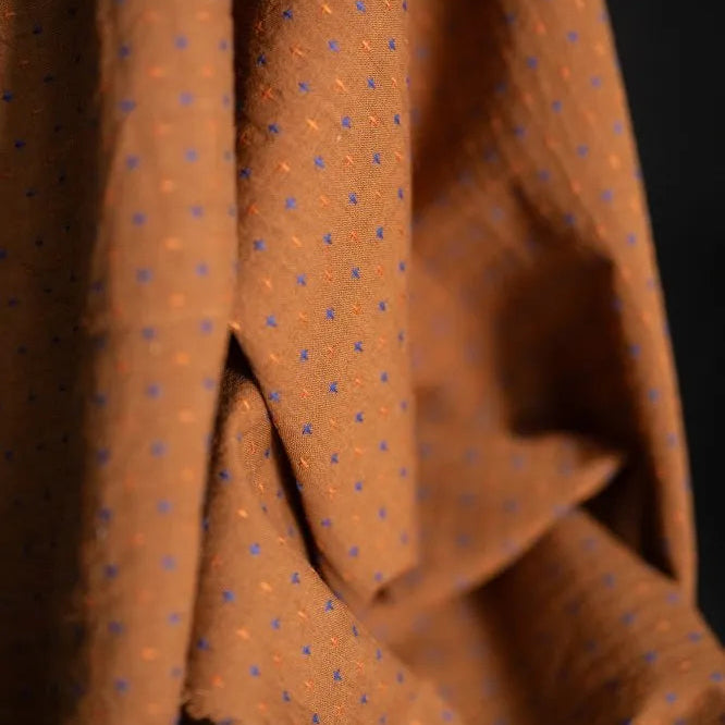 Rust Bobbette Organic Indian Cotton with Orange and Cobalt Blue woven Cross Stitch Detail. A close up of the draped fabric.