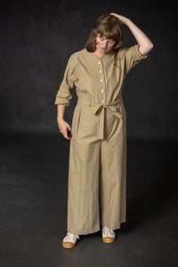 Woman wearing a beige cassidy jumpsuit against a dark background