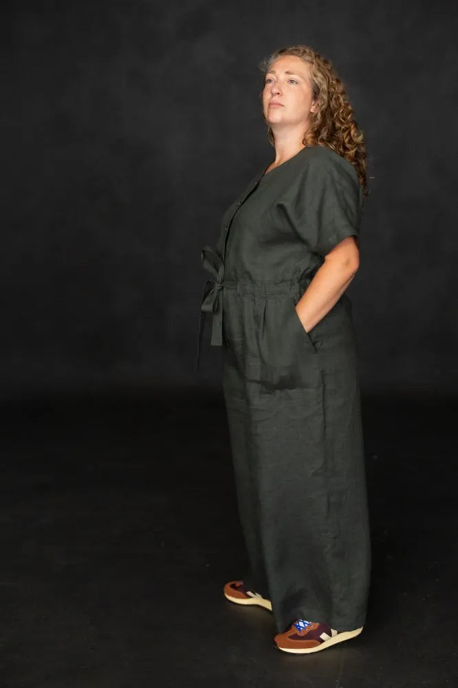 Person wearing a dark green cassidy jumpsuit against a black background