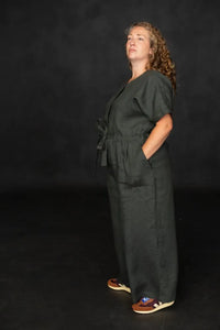 Person wearing a dark green cassidy jumpsuit against a black background