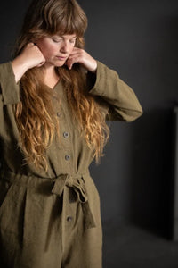Woman wearing a green long sleeved cassidy jumpsuit against a dark background