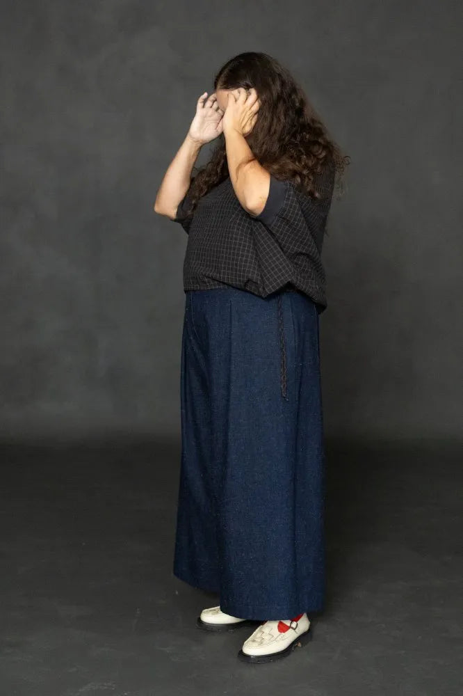 Person wearing a dark checked cirrus top and denim pants on a black background. The Cirrus Top sewing pattern by Merchant and Mills is available at Stitch Piece Loop, Australia.