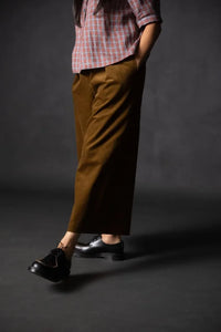 Person wearing a brown pair of Juno Trousers against a dark background. The Juno Trouser sewing pattern is by Merchant and Mills, and available at Stitch Piece Loop, Australia.