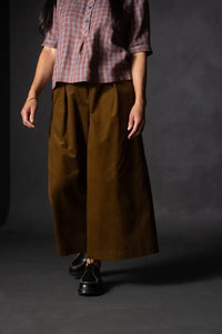 Person wearing a brown pair of Juno Trousers against a dark background. The Juno Trouser sewing pattern is by Merchant and Mills, and available at Stitch Piece Loop, Australia.