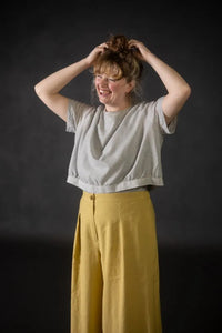 Person wearing a yellow pair of Juno Trousers against a dark background. The Juno Trouser sewing pattern is by Merchant and Mills, and available at Stitch Piece Loop, Australia.