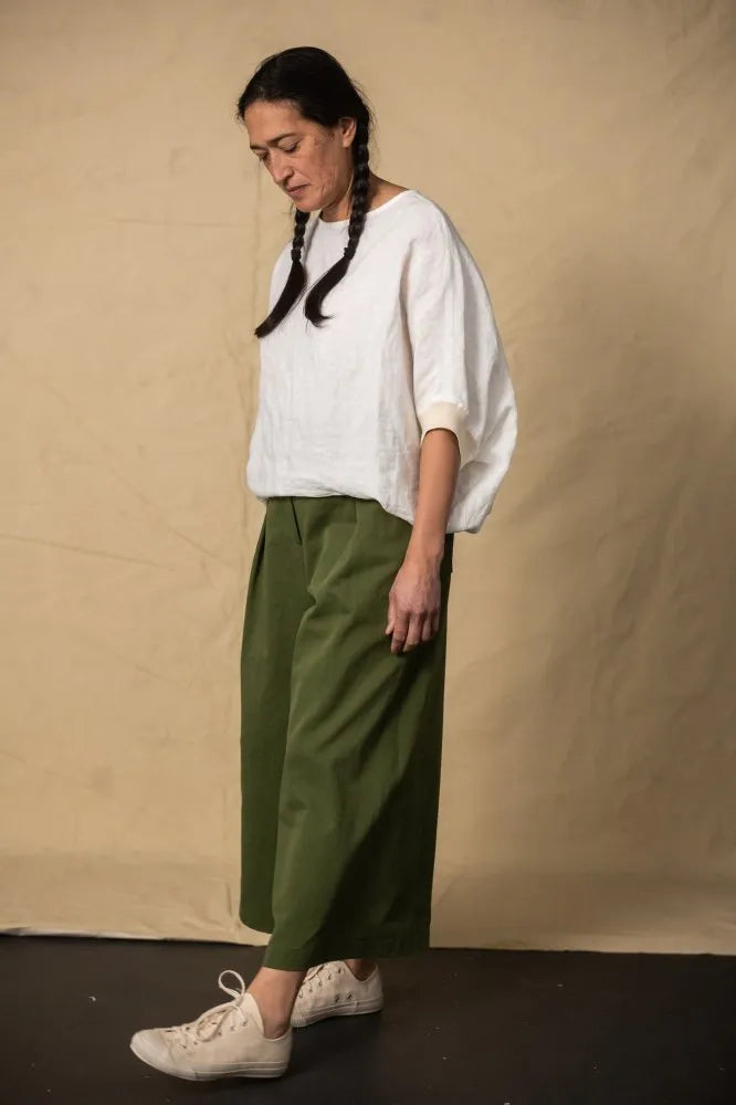 Person wearing a green pair of Juno Trousers against a dark background. The Juno Trouser sewing pattern is by Merchant and Mills, and available at Stitch Piece Loop, Australia.