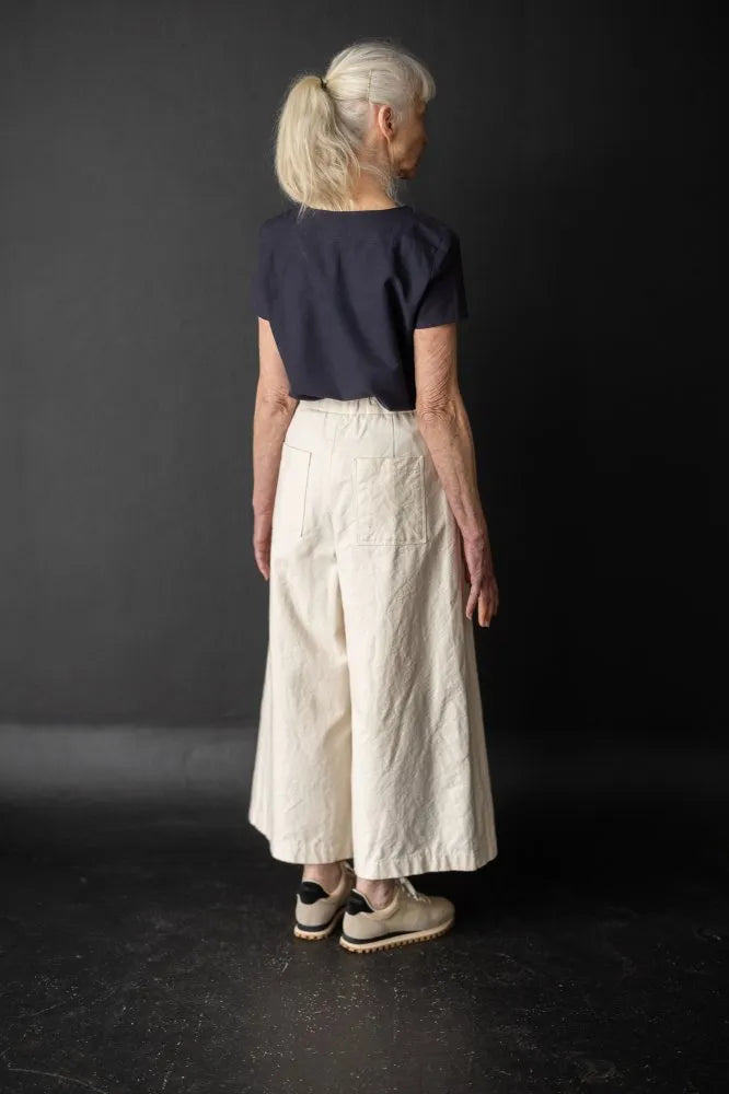 Person wearing a white pair of Juno Trousers against a dark background. The Juno Trouser sewing pattern is by Merchant and Mills, and available at Stitch Piece Loop, Australia.
