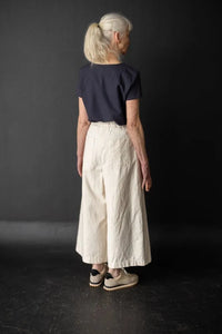 Person wearing a white pair of Juno Trousers against a dark background. The Juno Trouser sewing pattern is by Merchant and Mills, and available at Stitch Piece Loop, Australia.