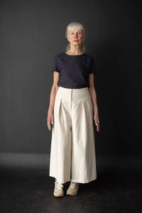 Person wearing a white pair of Juno Trousers against a dark background. The Juno Trouser sewing pattern is by Merchant and Mills, and available at Stitch Piece Loop, Australia.