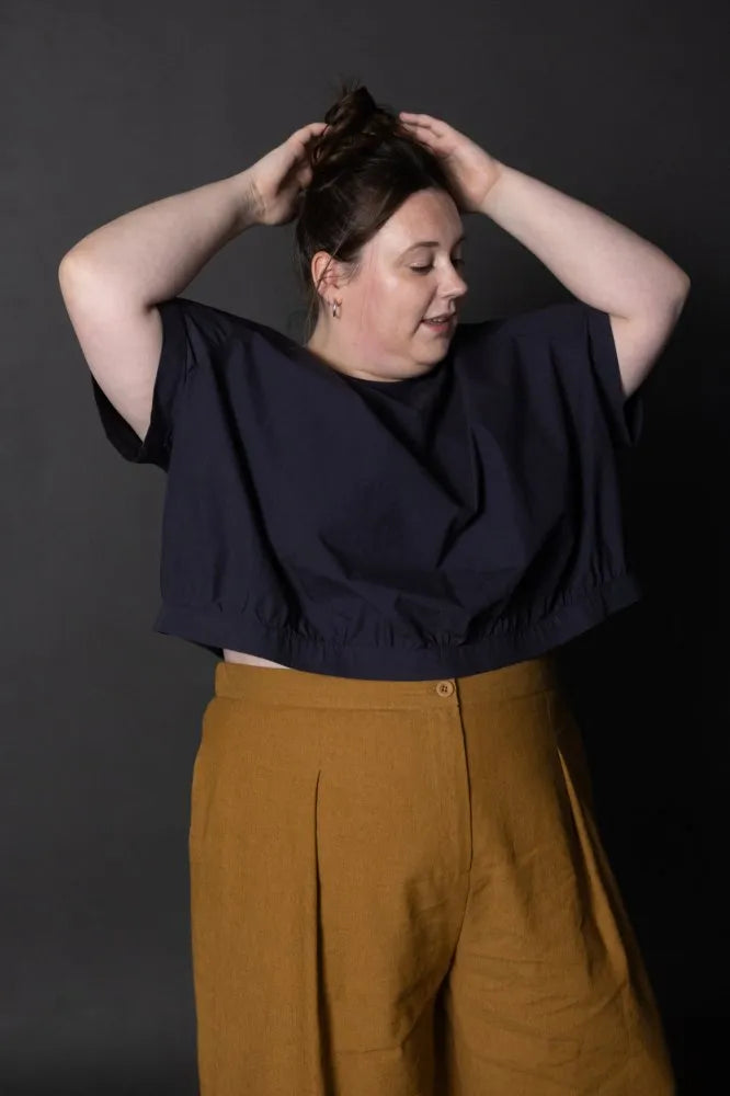 Person wearing a mustard yellow pair of Juno Trousers against a dark background. The Juno Trouser sewing pattern is by Merchant and Mills, and available at Stitch Piece Loop, Australia.