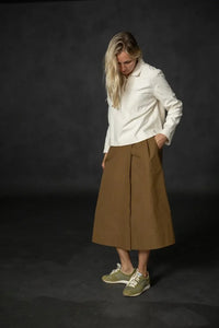 Woman wearing a structured brown Nevis skirt with a white top. The Nevis Skirt Sewing Pattern is designed by Merchant and Mills and available at Stitch Piece Loop Australia.