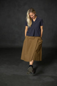 Woman wearing a structured brown Nevis skirt with a dark blue top. The Nevis Skirt Sewing Pattern is designed by Merchant and Mills and available at Stitch Piece Loop Australia.
