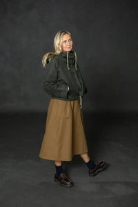 Woman wearing a structured brown Nevis skirt with a dark green parka. The Nevis Skirt Sewing Pattern is designed by Merchant and Mills and available at Stitch Piece Loop Australia.