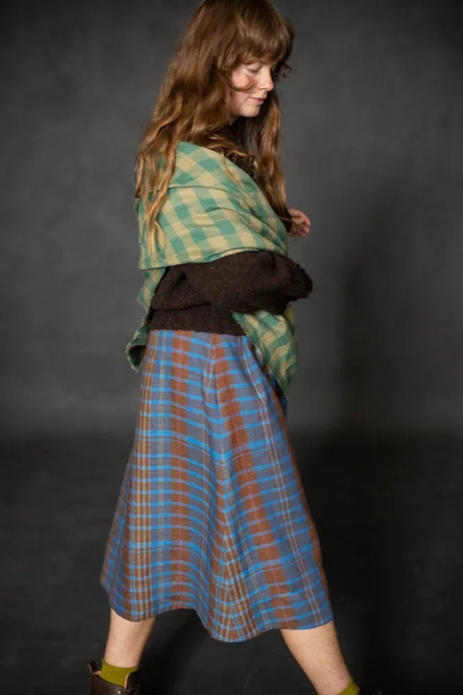 Woman wearing a blue plaid Nevis skirt with a dark brown knit top and boots. The Nevis Skirt Sewing Pattern is designed by Merchant and Mills and available at Stitch Piece Loop Australia.