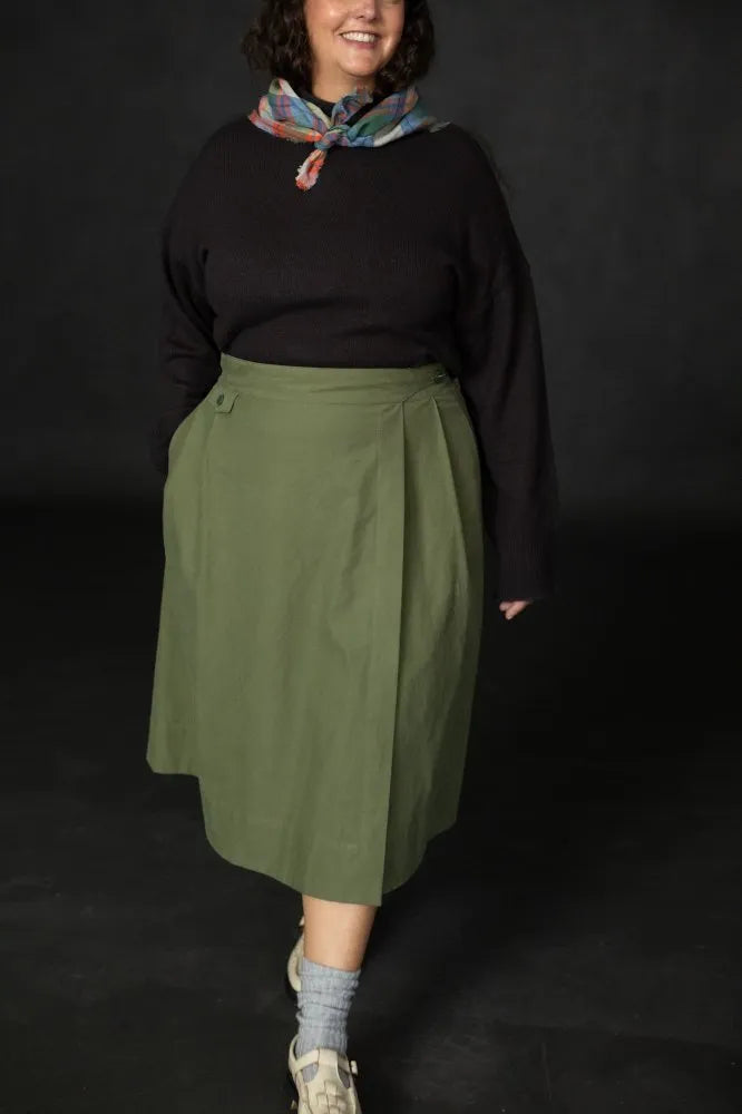 Woman wearing a structured green Nevis skirt with a dark blue top. The Nevis Skirt Sewing Pattern is designed by Merchant and Mills and available at Stitch Piece Loop Australia.