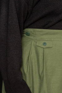 Woman wearing a structured green Nevis skirt with a dark blue top, highlighting the button closure detail at the waist. The Nevis Skirt Sewing Pattern is designed by Merchant and Mills and available at Stitch Piece Loop Australia.