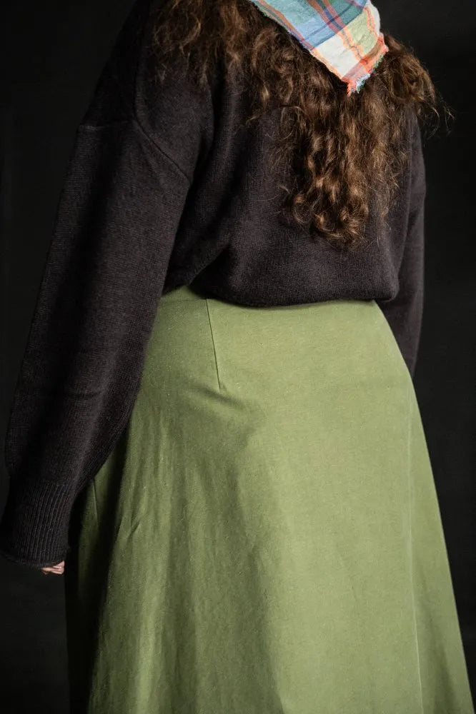 Woman wearing a structured green Nevis skirt with a dark blue top. The Nevis Skirt Sewing Pattern is designed by Merchant and Mills and available at Stitch Piece Loop Australia.