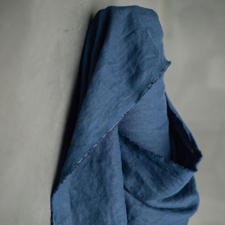 185 European Linen in Goodnight by Merchant and Mills. Available at Stitch Piece Loop – Australian Fabric Store. The image is a close up of the dark blue fabric draped over the fabric roll against a grey background.