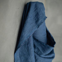 185 European Linen in Goodnight by Merchant and Mills. Available at Stitch Piece Loop – Australian Fabric Store. The image is a close up of the dark blue fabric draped over the fabric roll against a grey background.