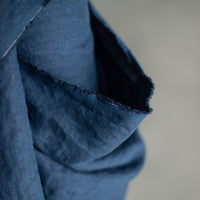 185 European Linen in Goodnight by Merchant and Mills. Available at Stitch Piece Loop – Australian Fabric Store. The image is a close up of the dark blue fabric draped over the fabric roll against a grey background.